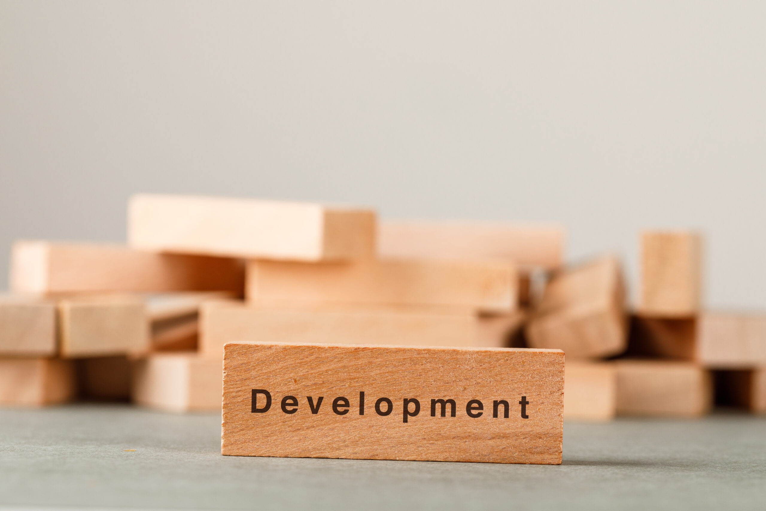 Business strategy and success concept with wooden blocks on grey and white background side view.